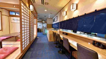 Una habitación tradicional japonesa con suelo de tatami, mesitas bajas y puertas correderas.