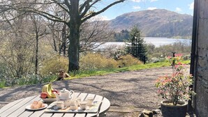 Eettafel met eten en thee, een hond, en een mooi uitzicht op een meer en bergen.