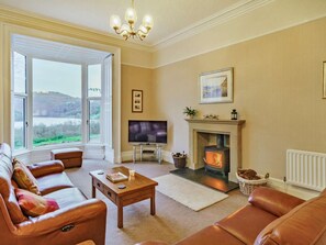 Ein Wohnzimmer mit einer Couch, einem Fernseher, einem Kamin und Blick ins Freie.
