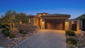 Une maison d’habitation avec une allée pavée, un garage et une entrée bien éclairée.
