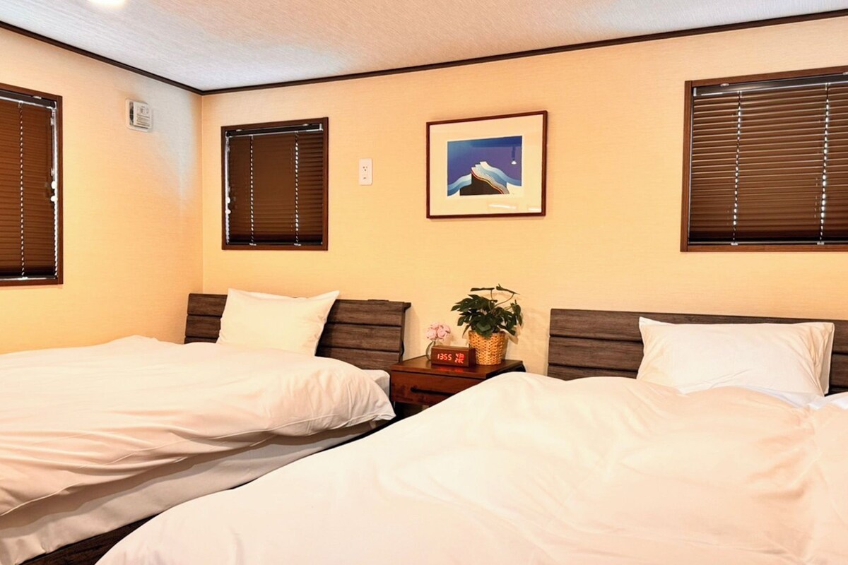 Una camera d'albergo con due letti, un comodino, una sveglia e un quadro appeso al muro.