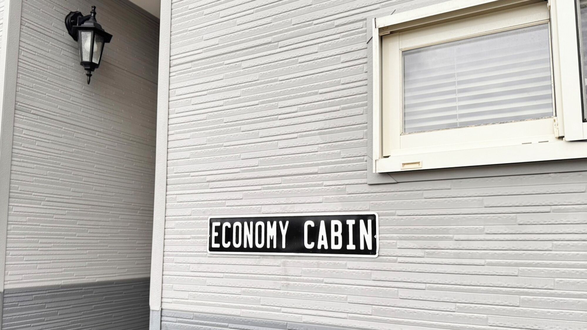 Un edificio con un letrero que dice 'ECONOMY CABIN' y una ventana con persianas.