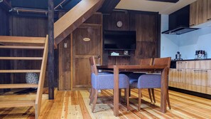 A rustic kitchen with wooden cabinets, a dining table with chairs, a ladder, and a clock on the wall. - Guest House Nodoka (Toyooka)