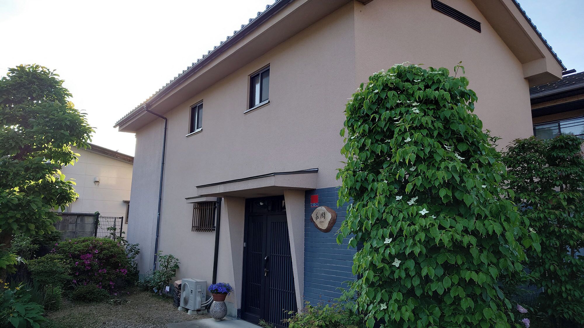 A two-story building with a beige exterior, a black door, and a small window.