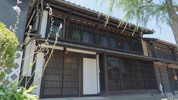 Ein traditionelles japanisches Gebäude mit Holzbauweise, einer Schiebetür und einem kleinen Garten.