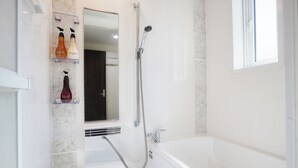 A modern bathroom with a bathtub, a shower, and a mirror above the sink. - Code Rooms Okinawa (Nakijin)