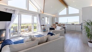 Un salon spacieux avec un canapé, une cheminée et une vue sur l’extérieur.
