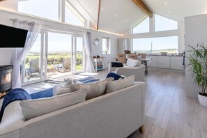 Ein geräumiges Wohnzimmer mit einer Couch, einem Kamin und Blick ins Freie.