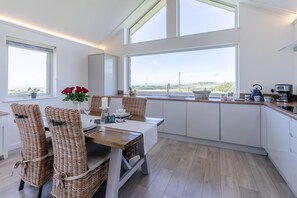 Eine moderne Küche mit Essbereich, großen Fenstern und Blick ins Grüne.
