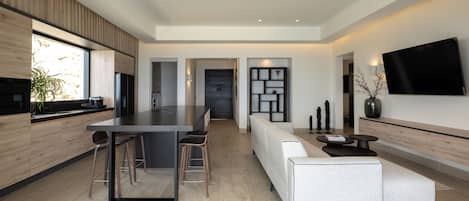 Una cocina moderna con una isla central, taburetes de bar, un sofá y un televisor de pantalla plana montado en la pared.