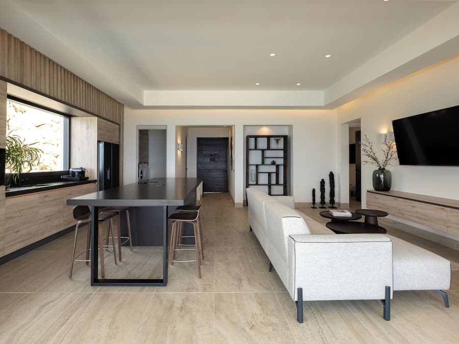 Una cocina moderna con una isla central, taburetes de bar, un sofá y un televisor de pantalla plana montado en la pared.