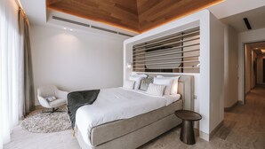 Un dormitorio moderno con una cama grande, una silla, una mesita pequeña y un estante empotrado.