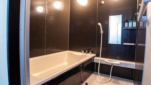 A modern bathroom with a bathtub, a shower, and a mirror.