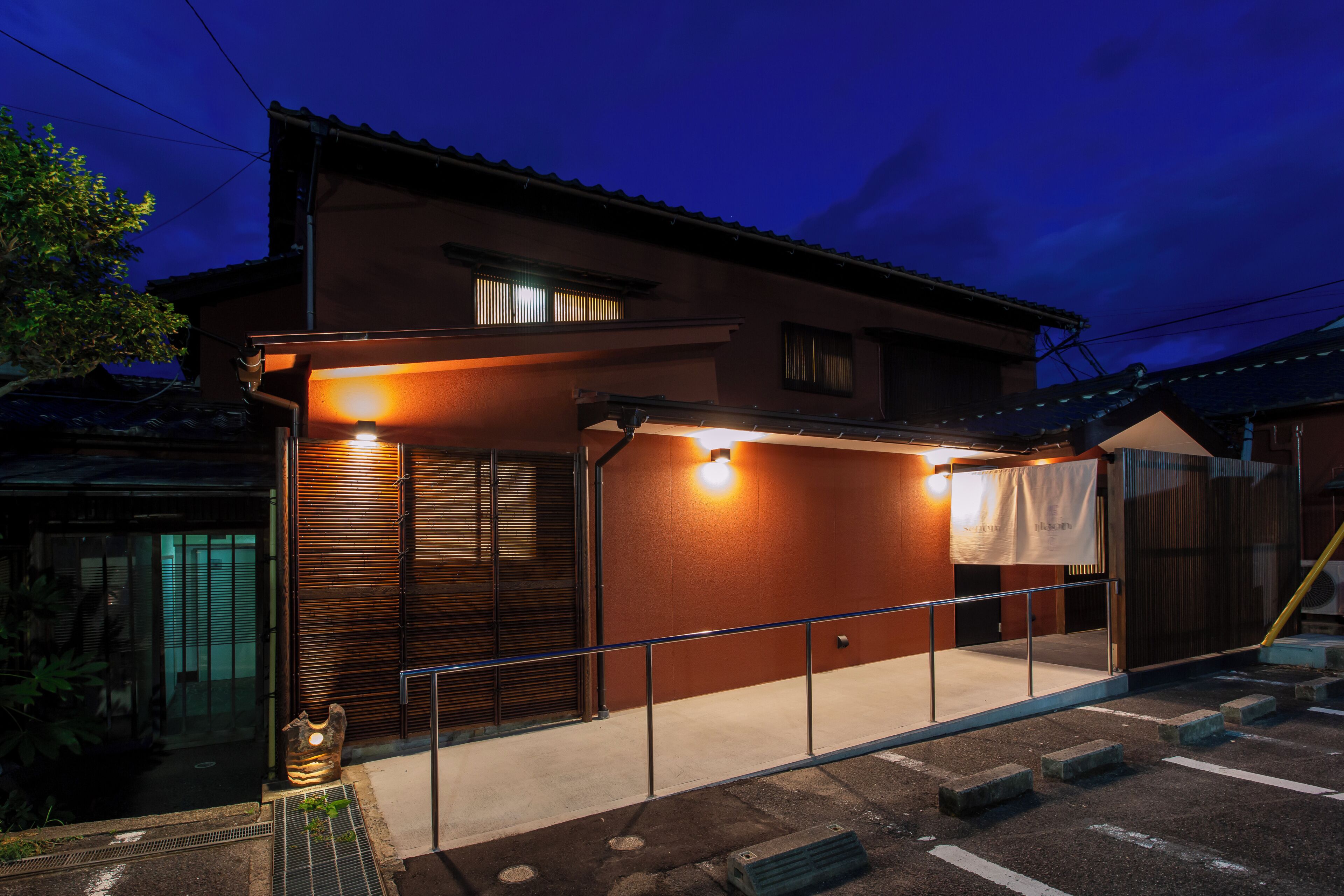 A residential building with a balcony, a small entrance, and a visible window.
