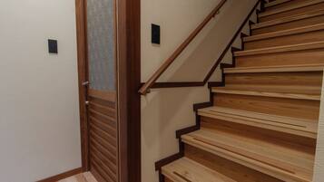 A wooden staircase with a handrail and a door with a patterned glass panel.