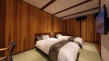 A hotel room with two beds, wooden paneling, a flat-screen TV, and a chair.
