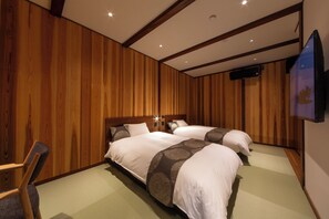Une chambre d’hôtel avec deux lits, des panneaux de bois au mur, un téléviseur à écran plat et une chaise.