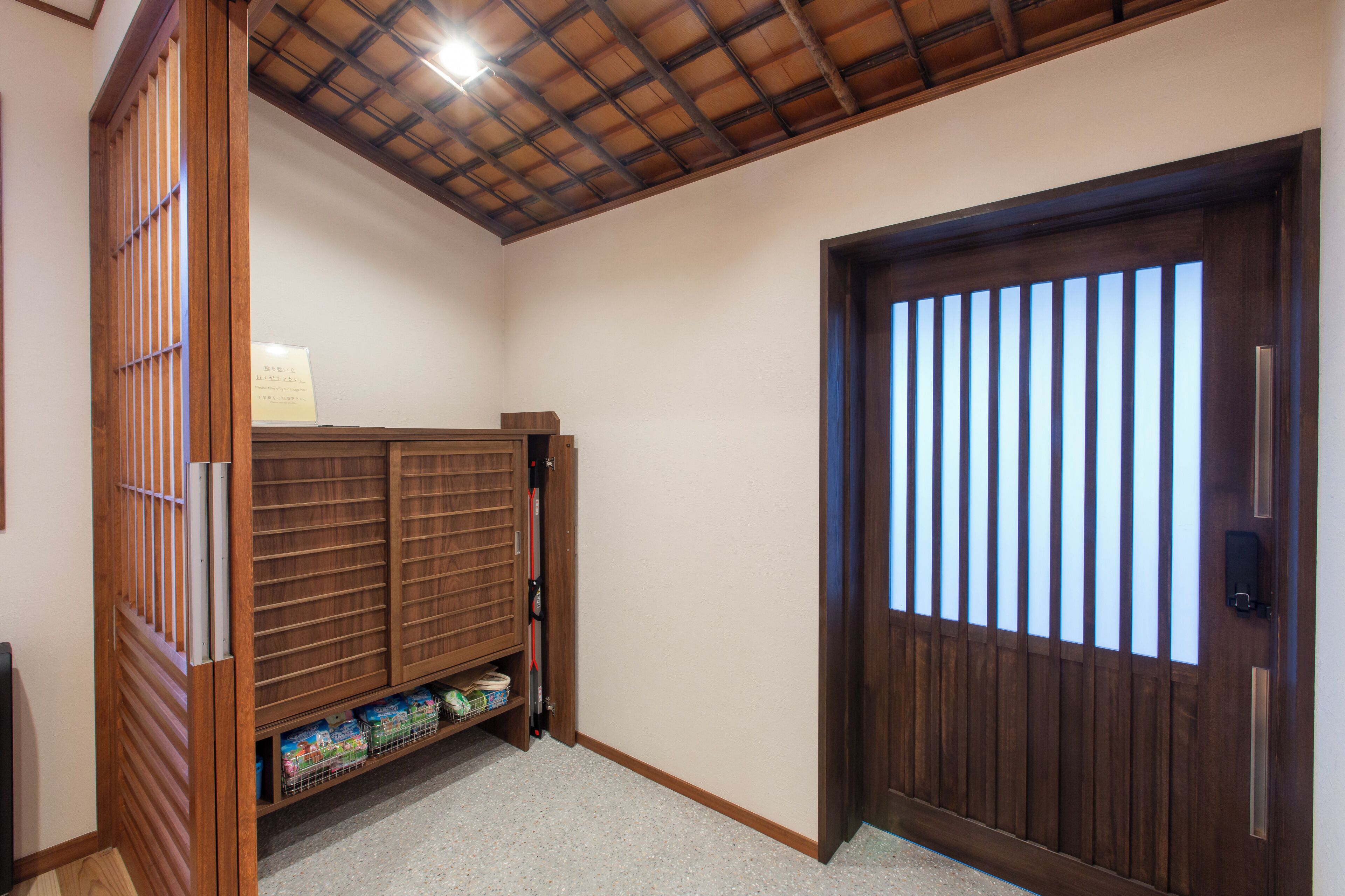 Una habitación con una puerta de madera, un estante con cajas de almacenamiento y un techo con estructura de vigas de madera.