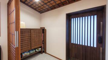 Una habitación con una puerta de madera, un estante con cajas de almacenamiento y un techo con estructura de vigas de madera.