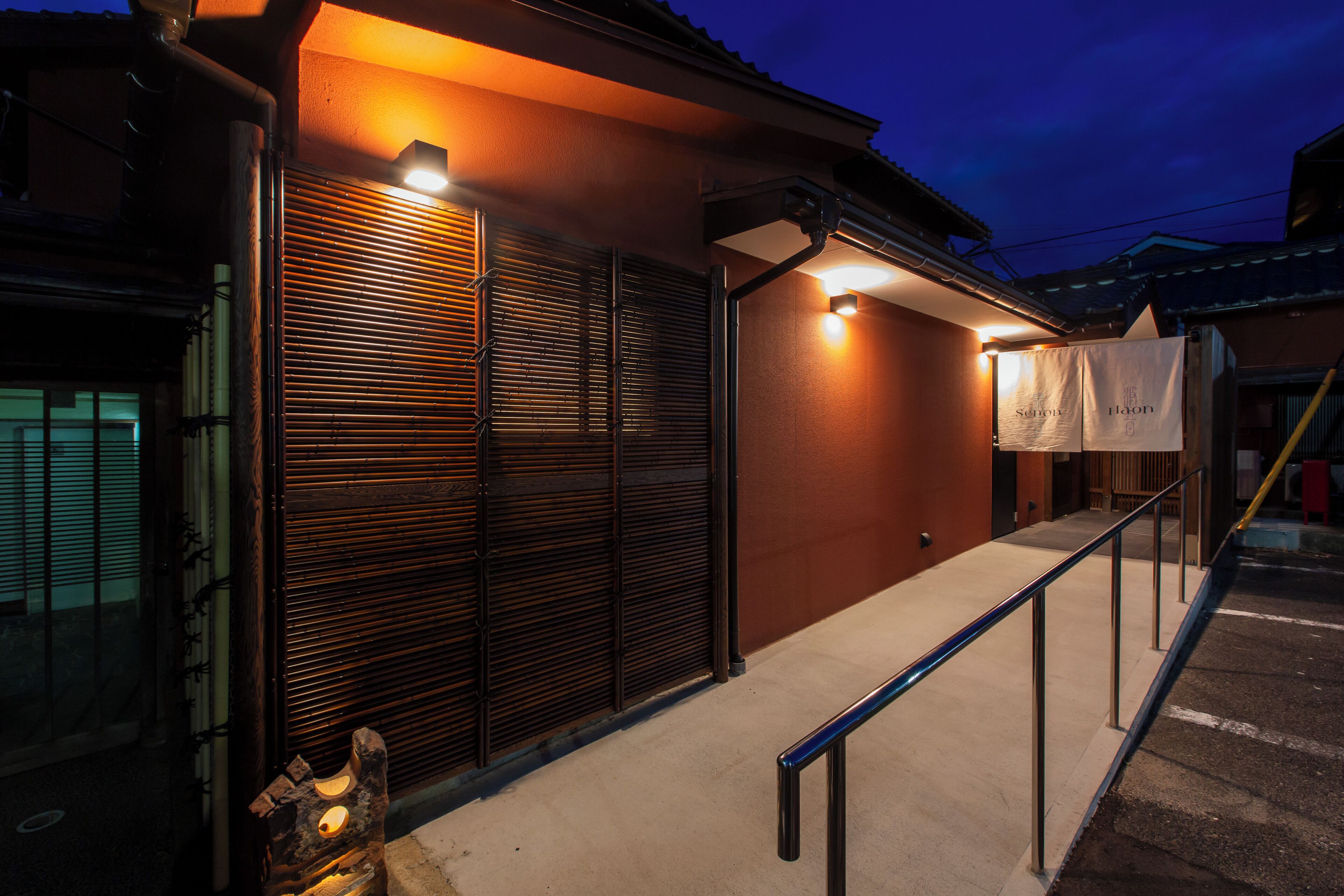 A building with a closed shutter, a metal railing, and a concrete ground.