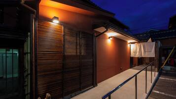 A building with a closed shutter, a metal railing, and a concrete ground.
