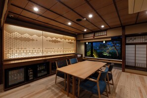 Une pièce de style japonais traditionnel, avec un sol recouvert de tatamis, une table basse et une vue sur la nature par la fenêtre.
