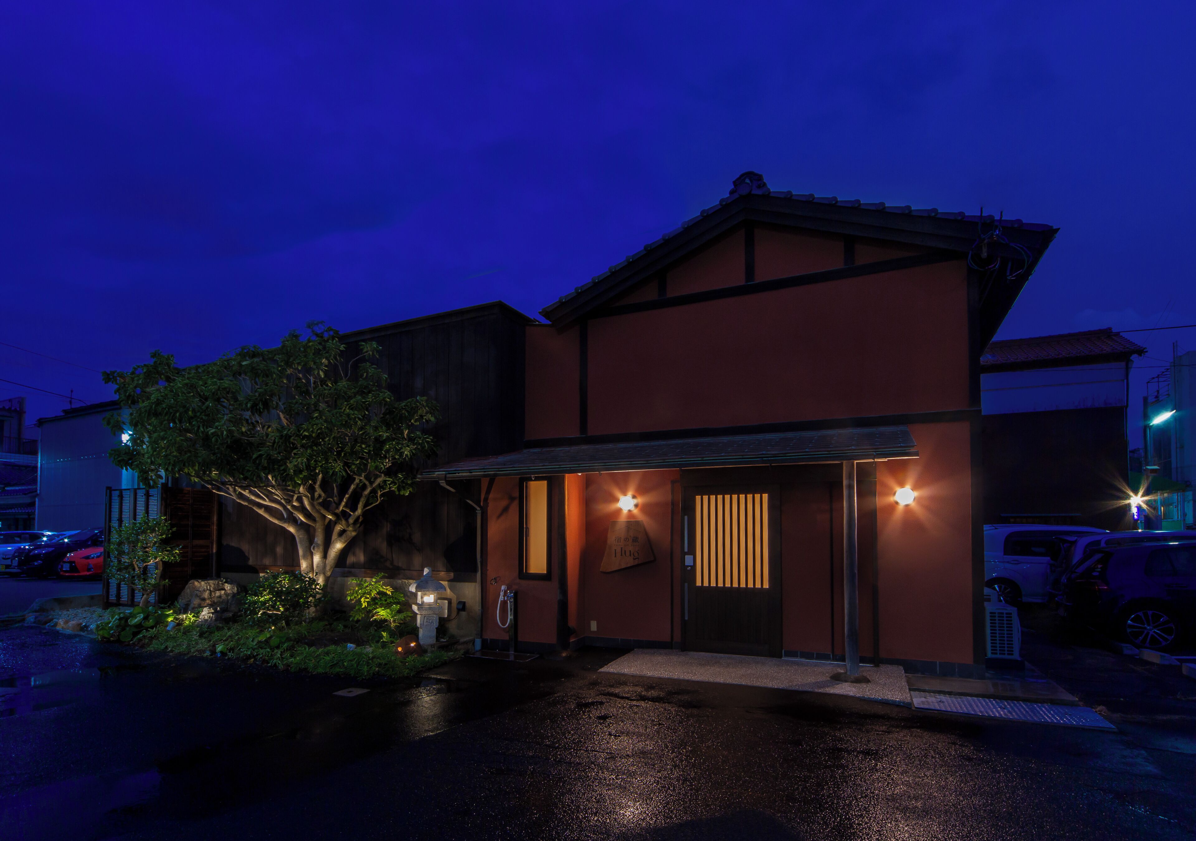 A building with a dark facade, a visible entrance, and a tree in front.