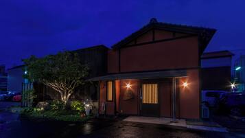 A building with a dark facade, a visible entrance, and a tree in front.