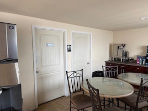 A compact kitchen with a refrigerator, a coffee machine, and a dining table with chairs. - Sunshine Inn (Yakima)