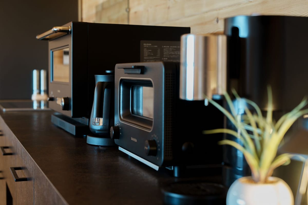 A kitchen with a coffee maker, a microwave, and a plant on the counter.