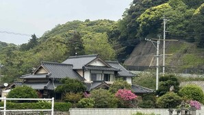 A traditional Japanese house with a tiled roof, surrounded by lush greenery and a stone wall. - Kurinoyakata (Kunisaki)
