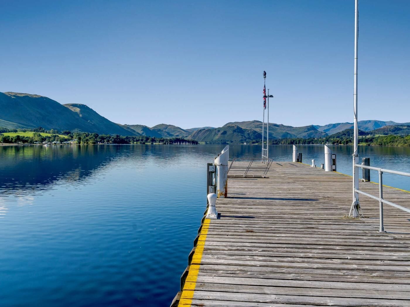 Een houten steiger die zich uitstrekt in kalm water, met bergen op de achtergrond.