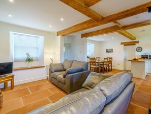Una sala de estar con sofá, televisión y comedor con mesa y sillas.