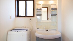 Bany amb rentadora blanca, un lavabo i un mirall.