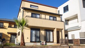 Un edifici residencial de dues plantes amb teulada plana, grans finestres i una palmera al primer terme.