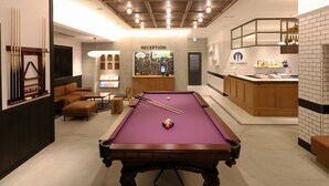 Mesa de bilhar com área de recepção e bar ao fundo.