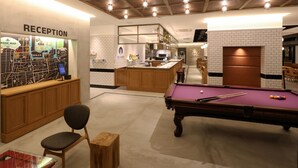 Uma área de recepção com um mapa, mesa de bilhar e bar.
