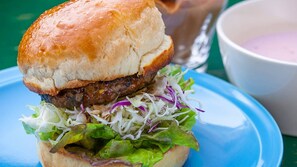 Un hamburger con lattuga e un panino su un piatto blu.