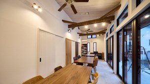 A spacious room with a long wooden table, chairs, ceiling fans, and large windows. - Troll Forest Stella (Nikko)