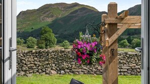 A stone wall, a wooden pergola with hanging flowers, and a mountainous landscape. - 1 Bed in Penrith (oc-85532) (Deepdale)