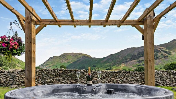 A hot tub under a wooden pergola with a stone wall and a mountainous landscape in the background. - 1 Bed in Penrith (oc-85532) (Deepdale)