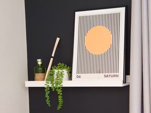 A shelf with a framed artwork, a bottle, and a plant. - *Sleeps 6* 4 Bedroom House + DriveContractors (Birmingham)