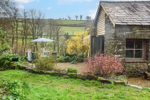 Ein Steinhaus mit Garten, einer Terrasse mit Gartenmöbeln und Blick ins Grüne.