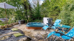 An outdoor patio with a hot tub, lounge chairs, and a stone deck. - 1 Bed in Llandysul (oc-85671) (Capel Dewi)