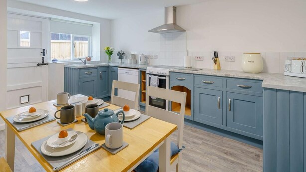 A modern kitchen with a dining area, featuring a stove, oven, and a large island with a sink. - 2 Bed in Cockermouth (oc-85680) (Blindcrake)