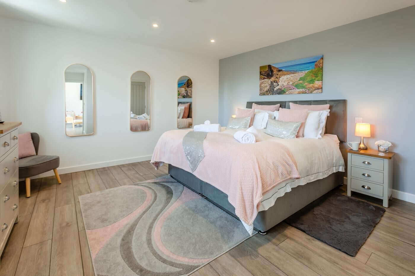 A bedroom with a bed, bedside tables, a dresser, and a painting on the wall.