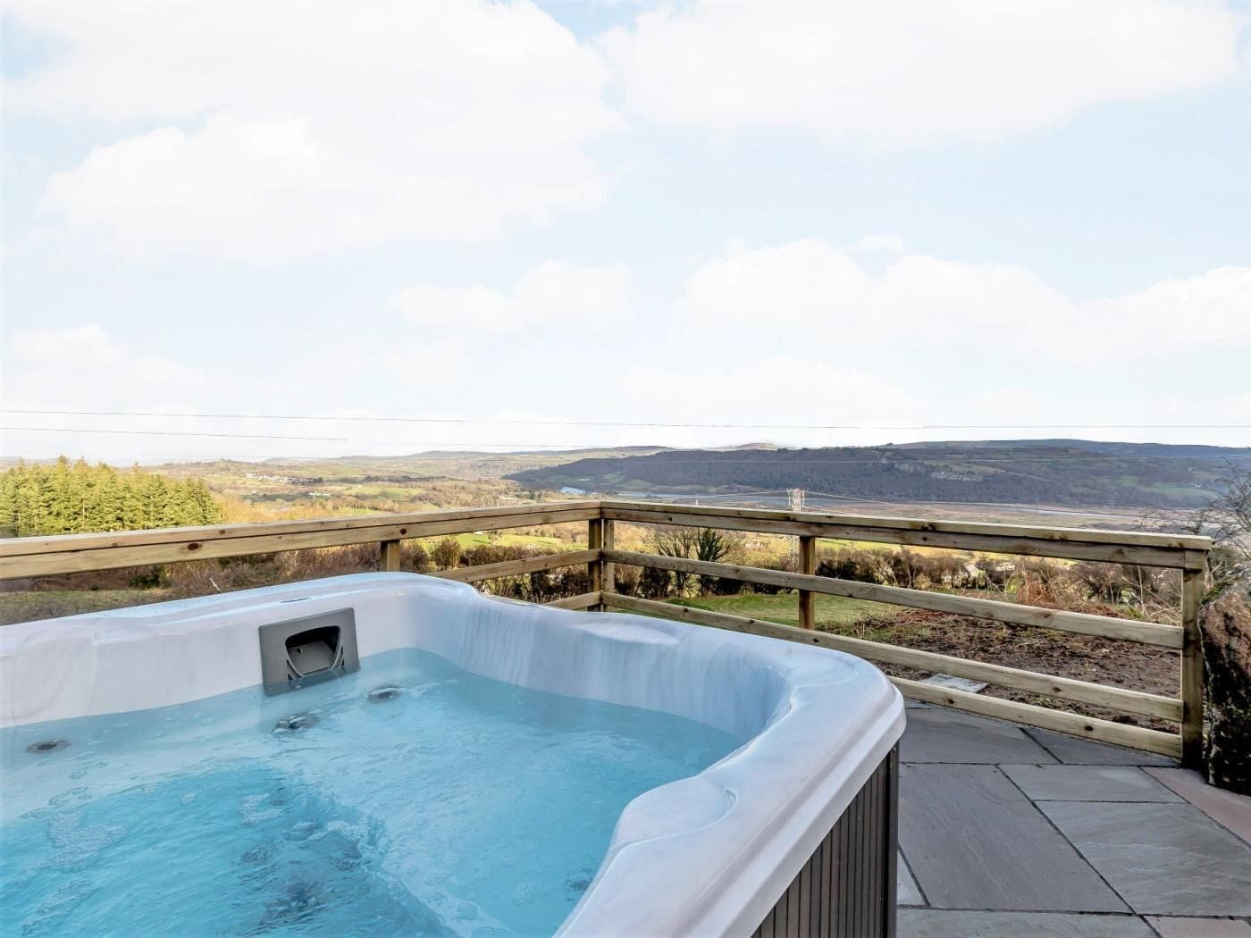 A hot tub on a deck with a view of a valley.