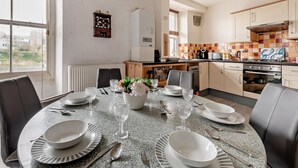 Una cocina moderna con comedor, que presenta una encimera de granito, electrodomésticos de acero inoxidable y vistas a la ciudad.