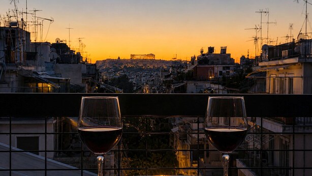 A balcony with two wine glasses and a candle, overlooking a cityscape at sunset. - Acropolis Panorama 2BRM Apartment by MΡS (Athina)