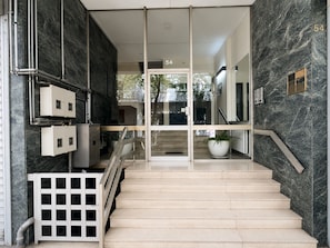 Ein modernes Interieur mit einer Marmortreppe, einem Glastür-Eingang und einem Schild mit der Nummer 54.
